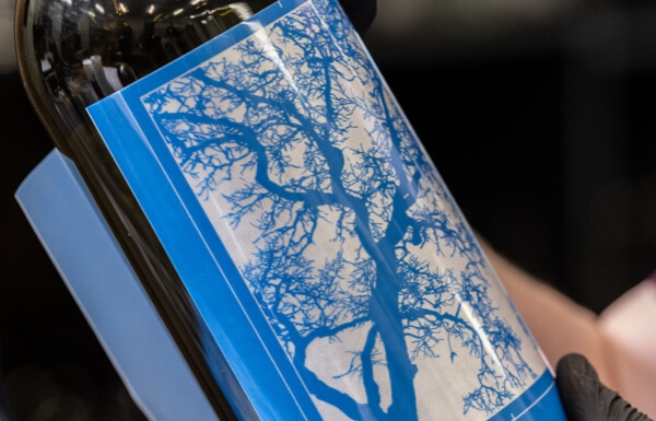 Bottle mockup with blue screen print stencil art applied, part of the design and printing process for custom wine packaging.
